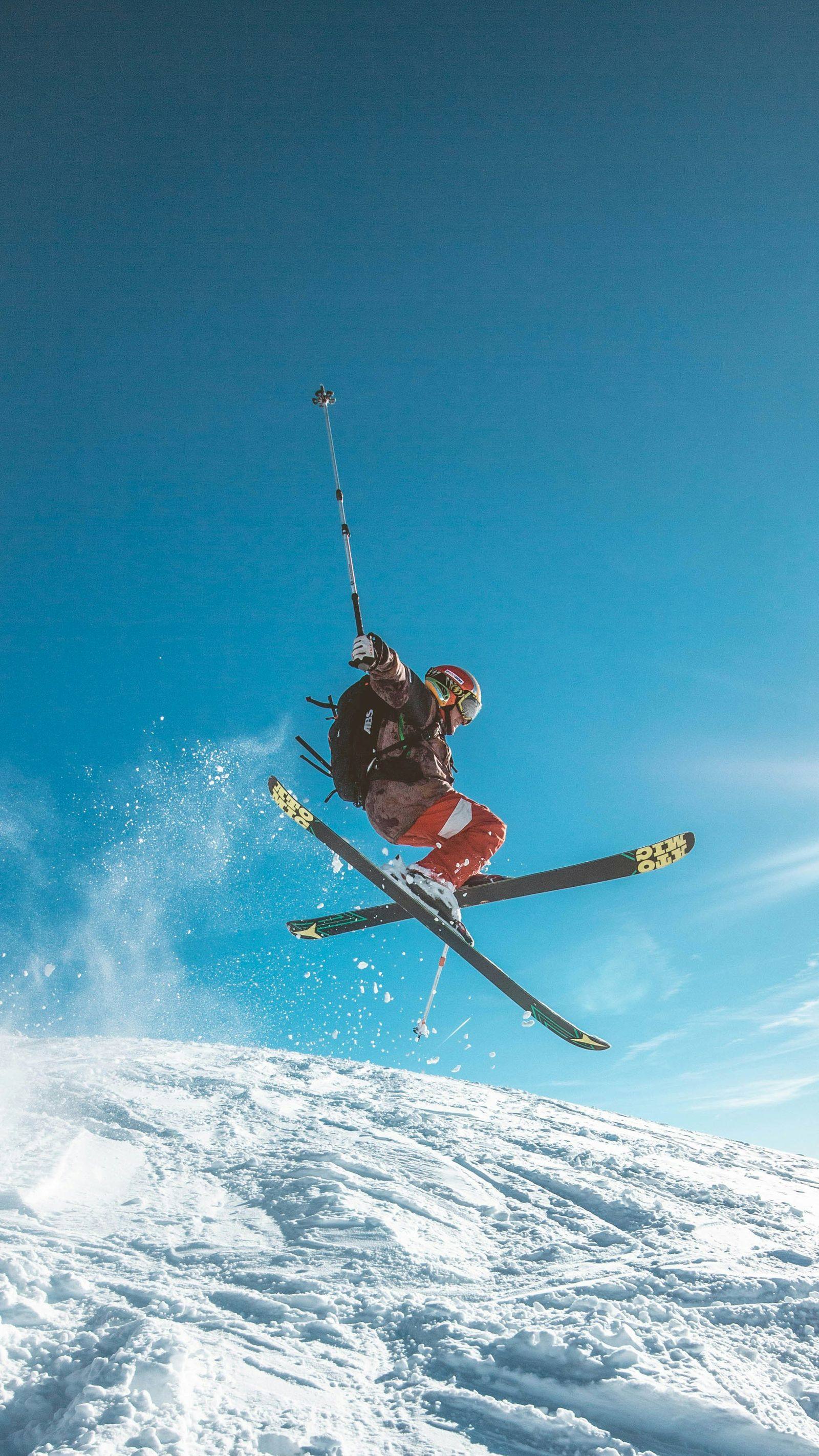 Skieur en plein saut au-dessus d'une pente enneigée, univers montagne et ski