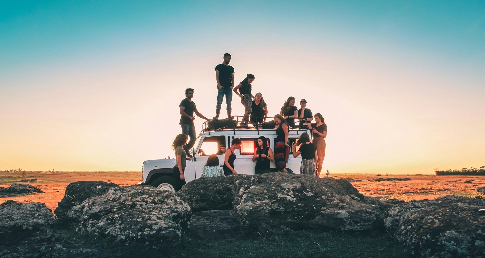 Groupe de voyageurs sur un van au coucher du soleil, univers van life et roadtrip